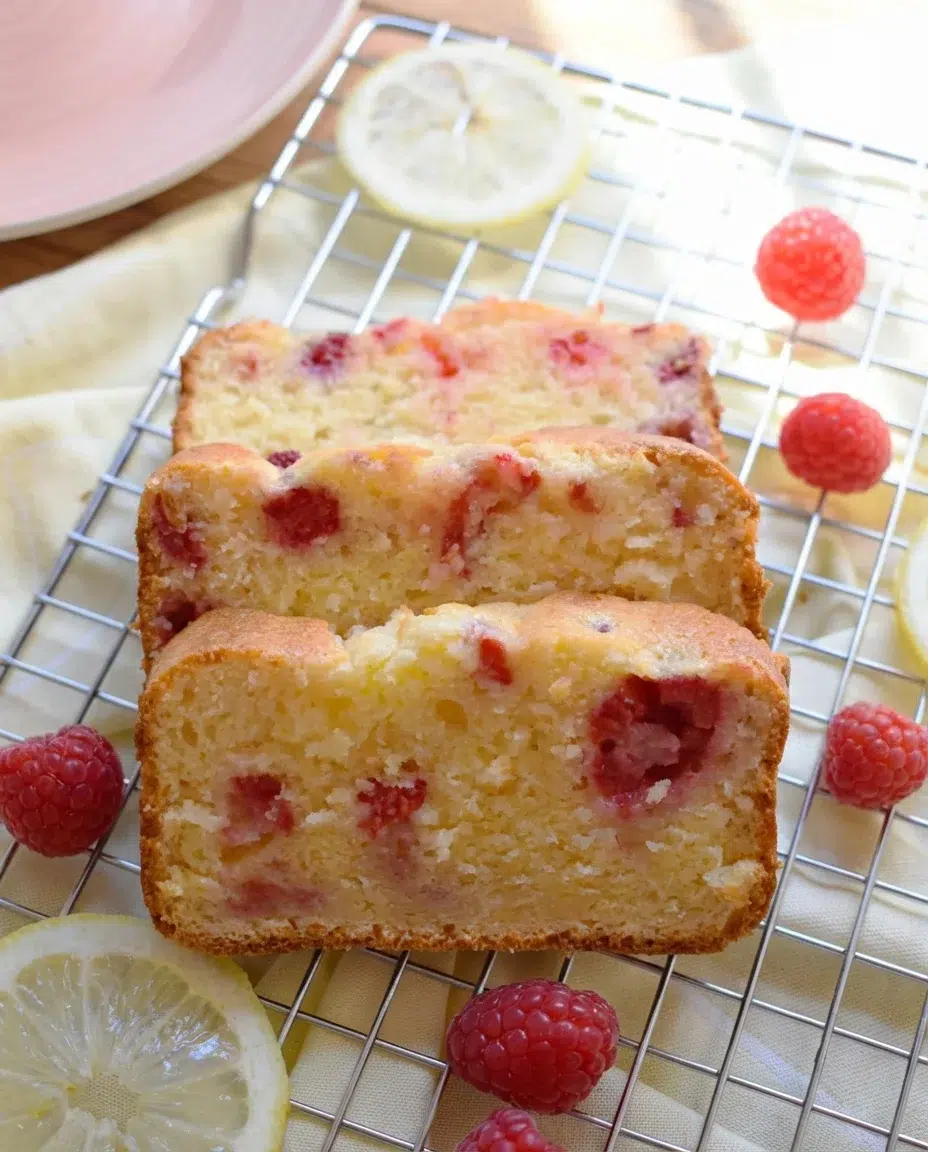 RASPBERRY-LEMON-LOAF-CAKE-IMAGE7-683x1024.jpg slices of raspberry-lemon loaf cake on a cooling rack with raspberries and lemon slices