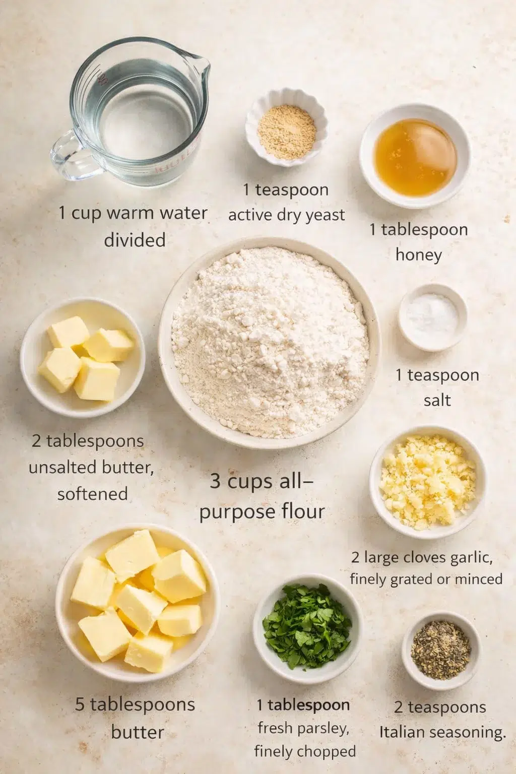 Measured ingredients arranged for Pull Apart Garlic Bread: 1 cup warm water, divided, 1 teaspoon active dry yeast, 1 tablespoon honey, 3 cups all-purpose flour, 2 tablespoons unsalted butter, softened, 1 teaspoon salt