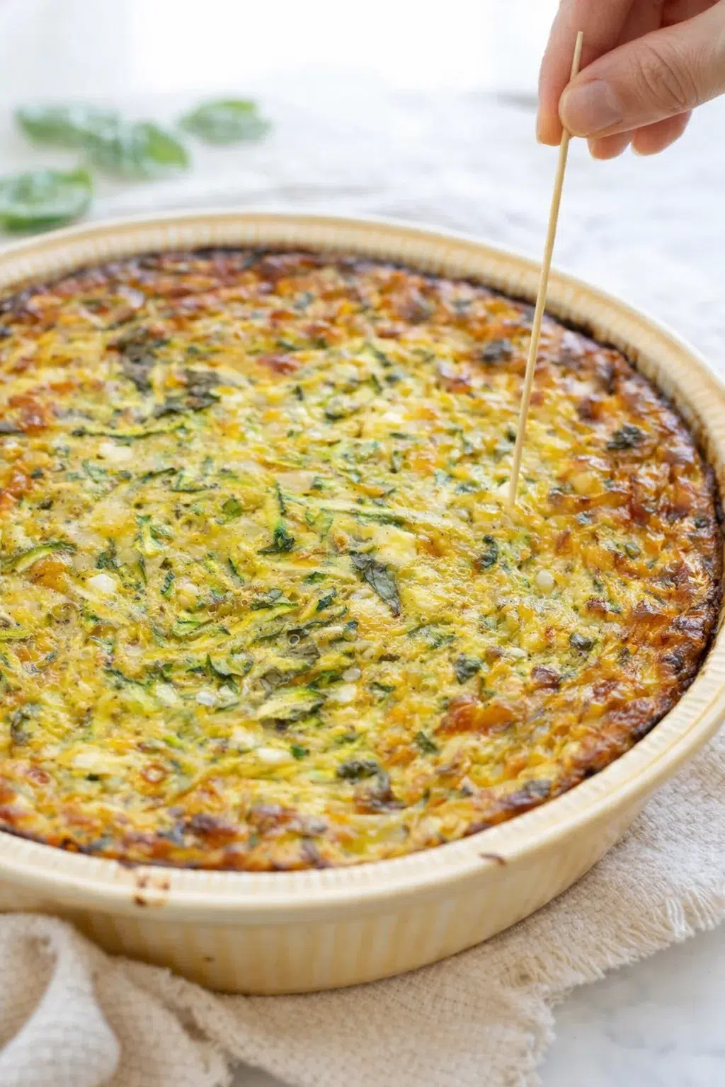 step-process-placeholder-13-13.png Hand inserting a toothpick into the quiche center to check doneness before cooling.