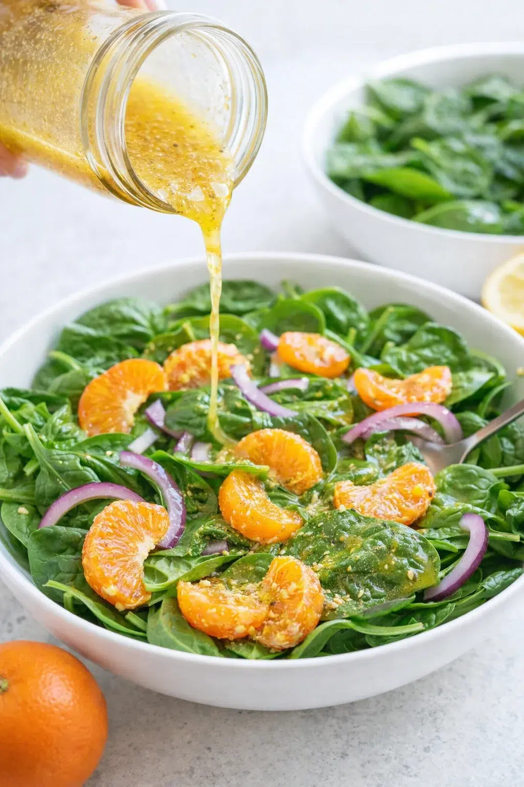 step-process-placeholder-9-12.png Whisked lemon-honey mustard dressing in jar being poured over spinach with mandarins and red onion.