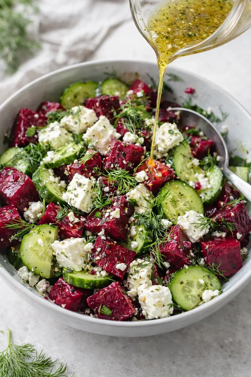 step-process-placeholder-5-7.png Large bowl with diced roasted beets, crumbled feta and dill, dressing being poured and gently tossed.