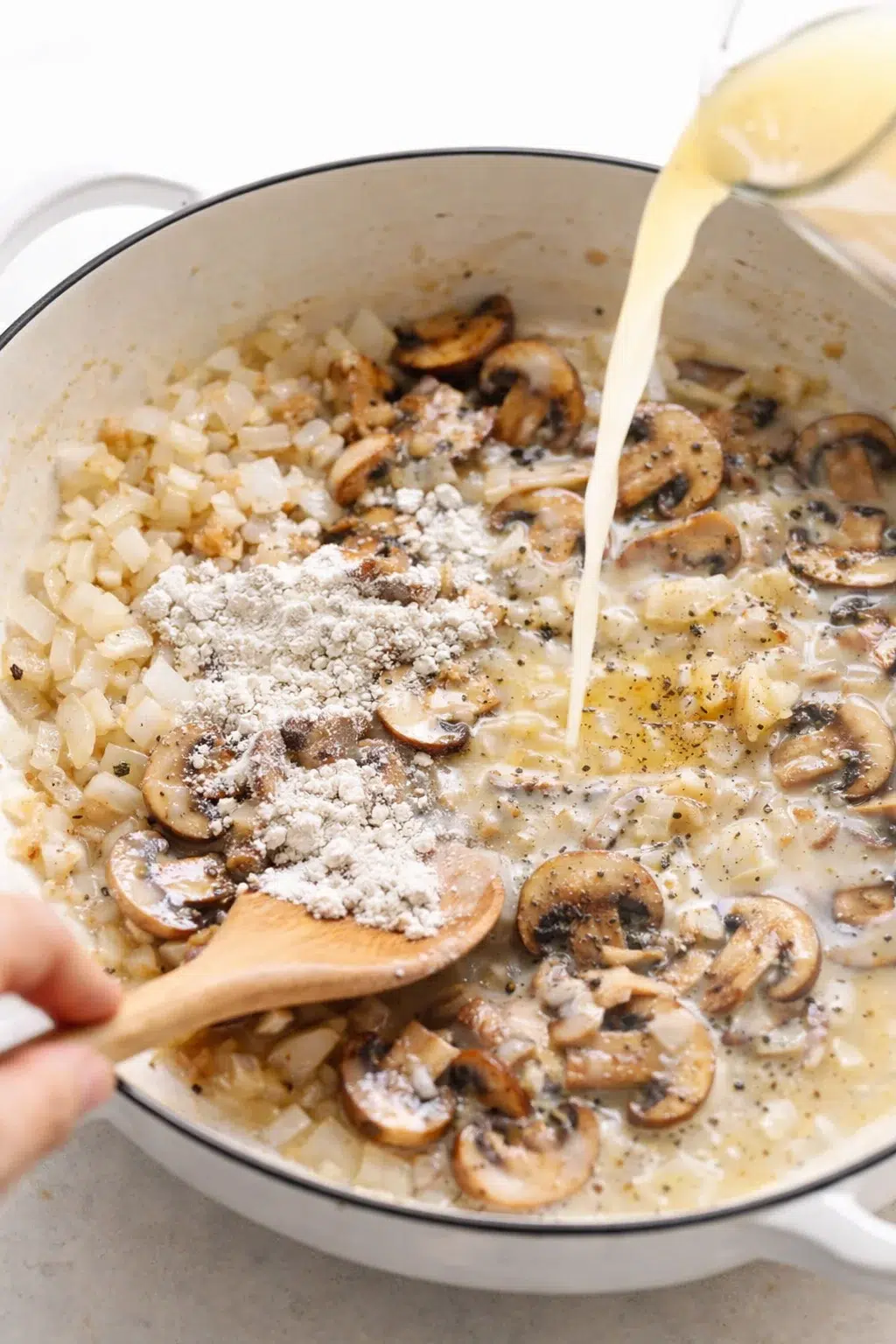 step-process-placeholder-5-8.png Onions and mushrooms sautéing in skillet, flour sprinkled on top ready to be stirred in.