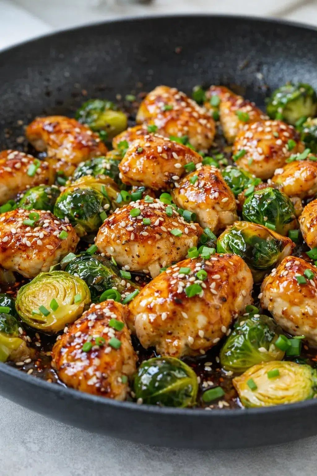 Brussels sprouts and chicken coated in thick sticky honey-garlic glaze, topped with sesame and green onions