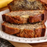 Two thick slices of banana bread with a golden crust on a white patterned plate.