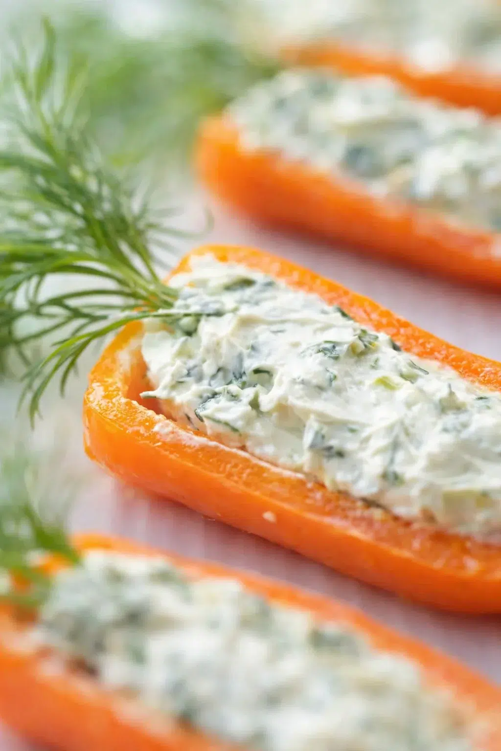 Close-up of orange carrot boat with herbed cheese filling and dill garnish