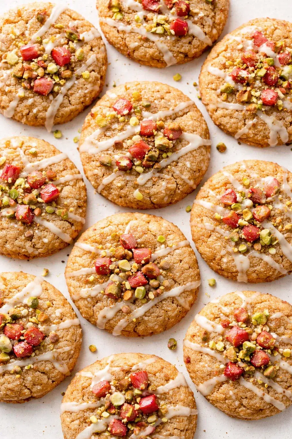 rounded cookies topped with white icing, chopped pistachios, and red cranberries photographed from above