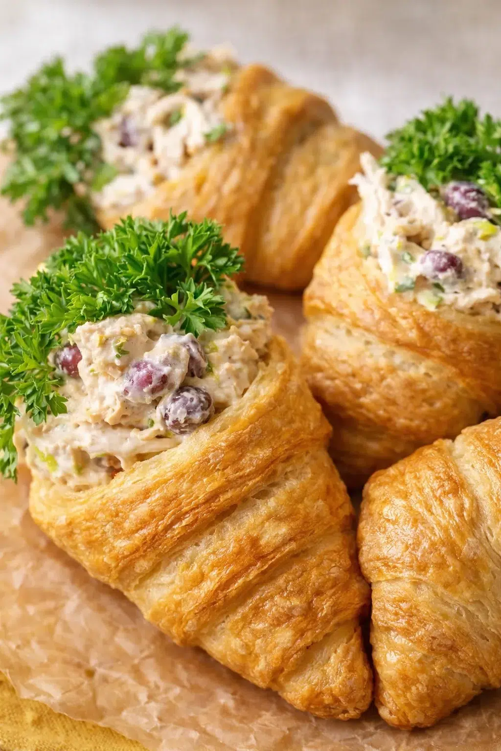 Golden croissant boats filled with creamy chicken salad and parsley garnish