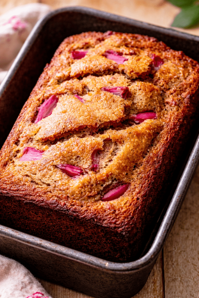 golden loaf topped with crumb streusel and pink rhubarb pieces