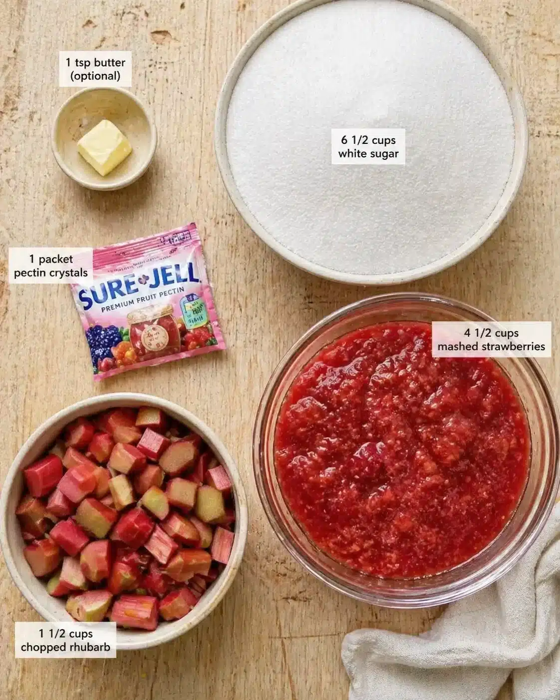 top-down view of ingredients for rhubarb-strawberry jam: chopped rhubarb, mashed strawberries, sugar, butter, and pectin.