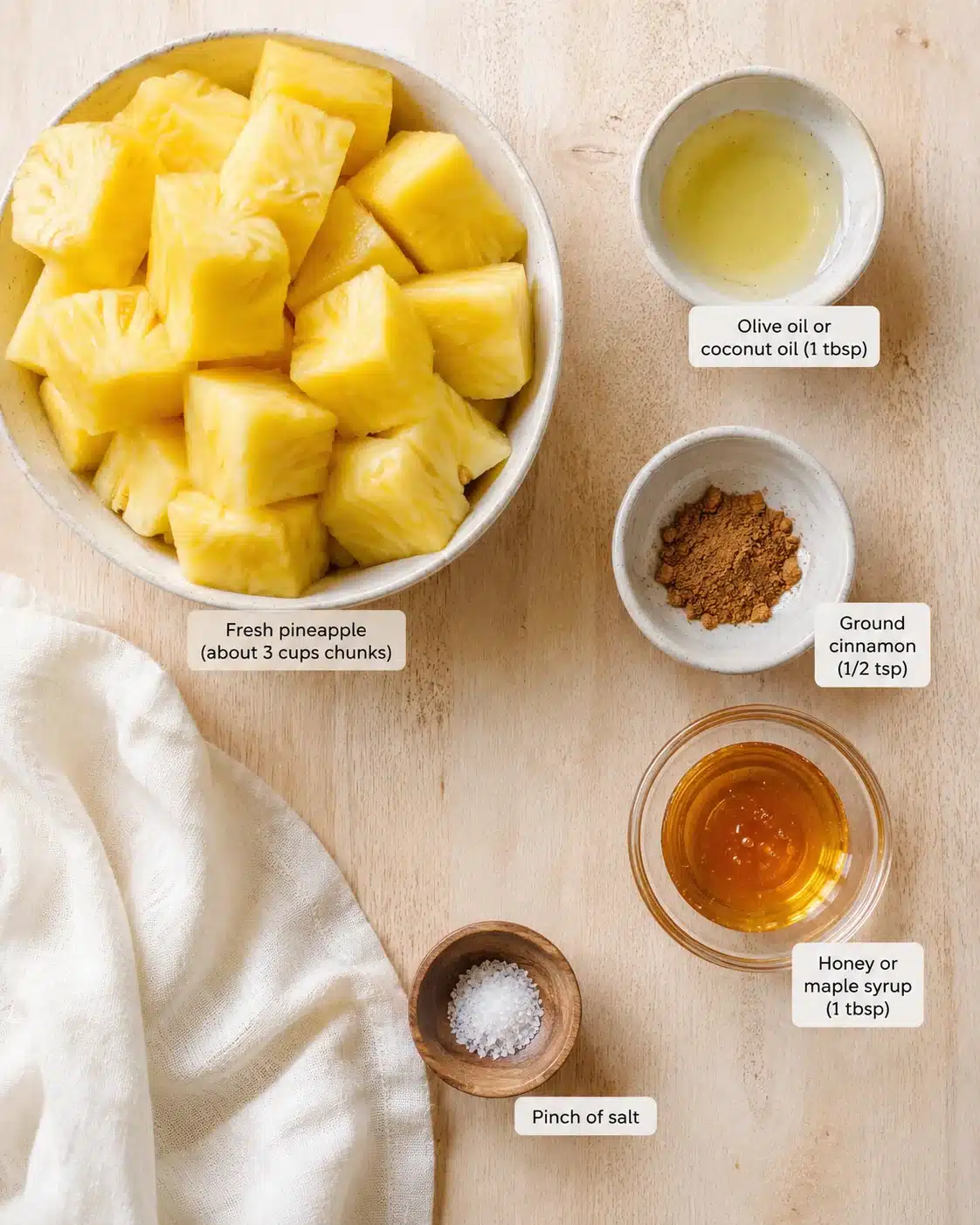 Top-down view of pineapple chunks with oil, cinnamon, honey, and salt on a wooden table